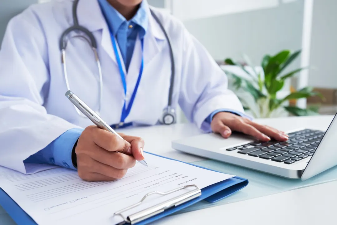 Médica preenchendo um formulário ao lado do notebook